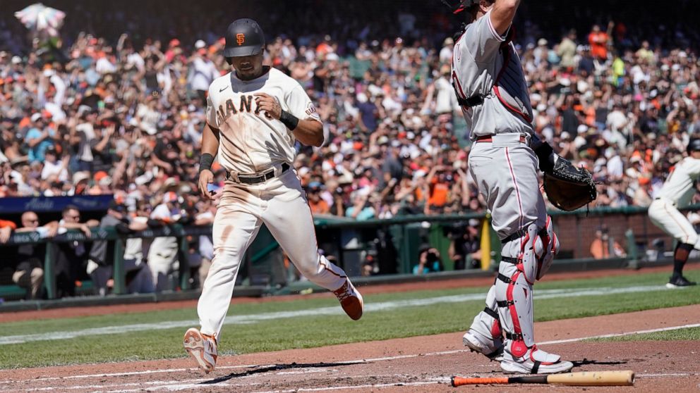 San Francisco Giants' LaMonte Wade Jr., left, scores past Philadelphia Phillies catcher J.T. Realmuto during the third inning of a baseball game in San Francisco, Saturday, Sept. 3, 2022. (AP Photo/Jeff Chiu)