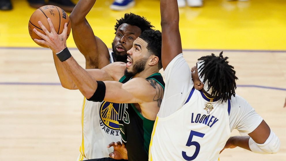Boston Celtics forward Jayson Tatum, middle, shoots against Golden State Warriors forward Andrew Wiggins, rear, and center Kevon Looney (5) during the second half of Game 5 of basketball's NBA Finals in San Francisco, Monday, June 13, 2022. (AP Photo