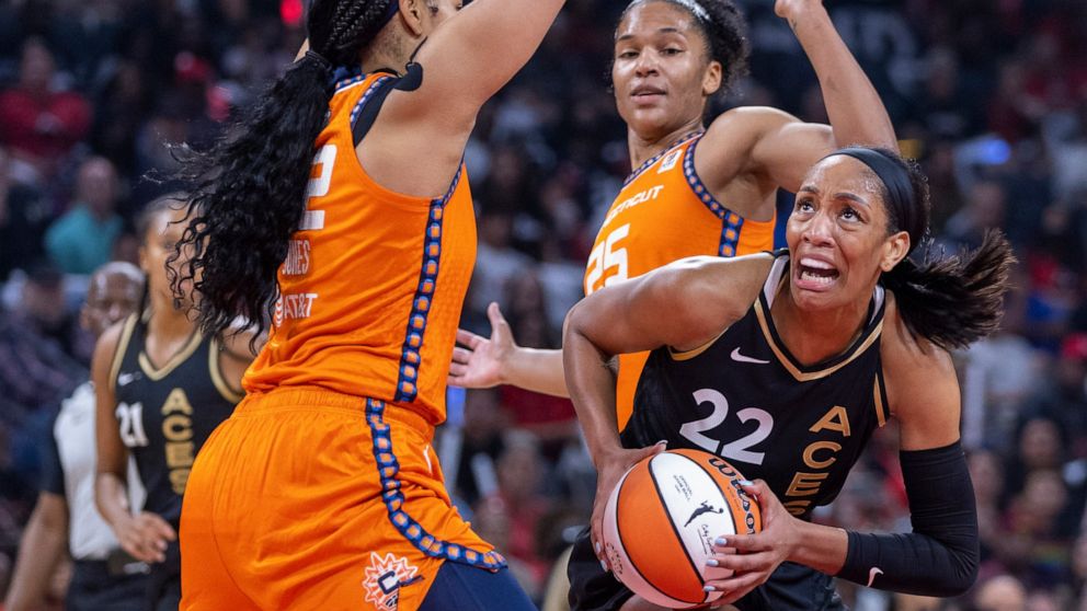 Las Vegas Aces forward A'ja Wilson (22) looks for a shot between Connecticut Sun center Brionna Jones (42) and forward Alyssa Thomas (25) during the first half in Game 1 of a WNBA basketball final playoff series Sunday, Sept. 11, 2022, in Las Vegas. 