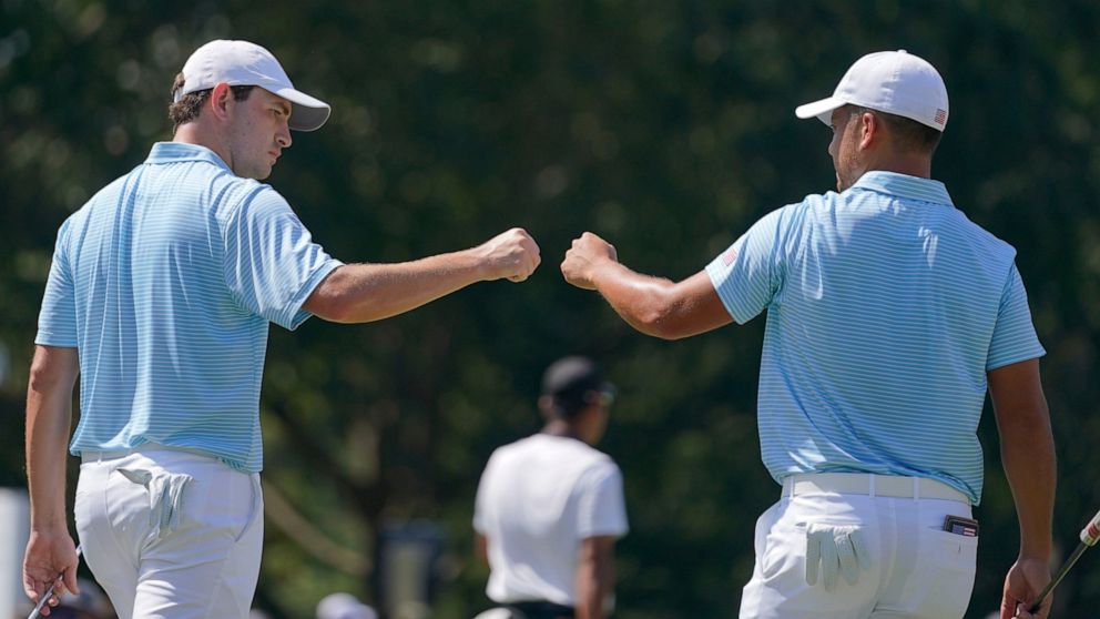 Patrick Cantlay, left, and Xander Schauffele celebrate on the fifth green during their foursomes match at the Presidents Cup golf tournament at the Quail Hollow Club, Thursday, Sept. 22, 2022, in Charlotte, N.C. (AP Photo/Julio Cortez)