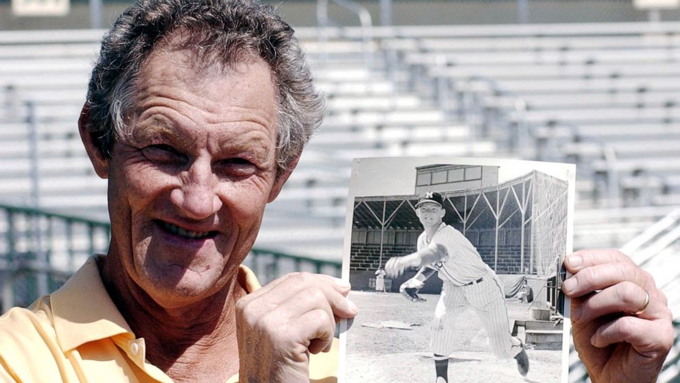 Former major league pitcher Jim Kaat poses with a photo of himself at age 19 before a spring training baseball game between the Houston Astros and the Florida Marlins in Jupiter, Fla., March 22, 2004. Minnesota Twins broadcaster Kaat referred to New 
