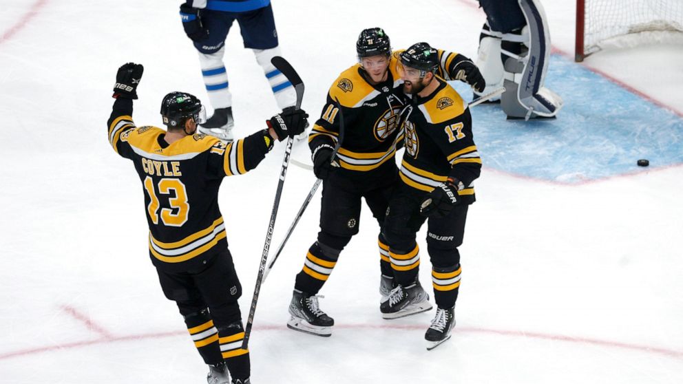 Boston Bruins left wing Nick Foligno (17) is congratulated for his goal against the Winnipeg Jets by Trent Frederic (11) and Charlie Coyle (13) during the third period of an NHL hockey game Thursday, Dec. 22, 2022, in Boston. (AP Photo/Mary Schwalm)