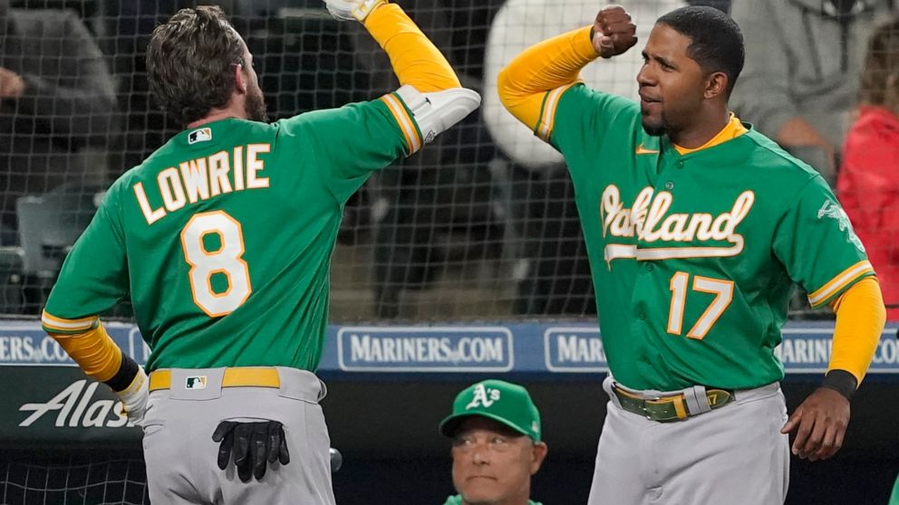 Oakland Athletics' Jed Lowrie (8) is greeted at the dugout by Elvis Andrus (17), after Lowrie hit a two-run home run during the fifth inning of a baseball game against the Seattle Mariners, Tuesday, May 24, 2022, in Seattle. Andrus hit a solo home ru