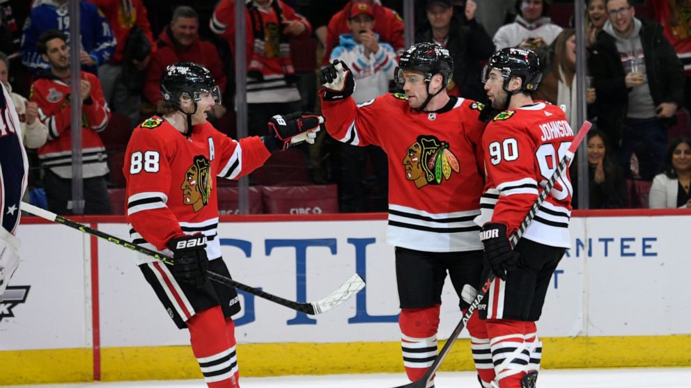 Chicago Blackhawks' Max Domi (13) celebrates with Patrick Kane (88) and Tyler Johnson (90) after scoring against the Columbus Blue Jackets during the first period of an NHL hockey game Friday, Dec. 23, 2022, in Chicago. (AP Photo/Paul Beaty)
