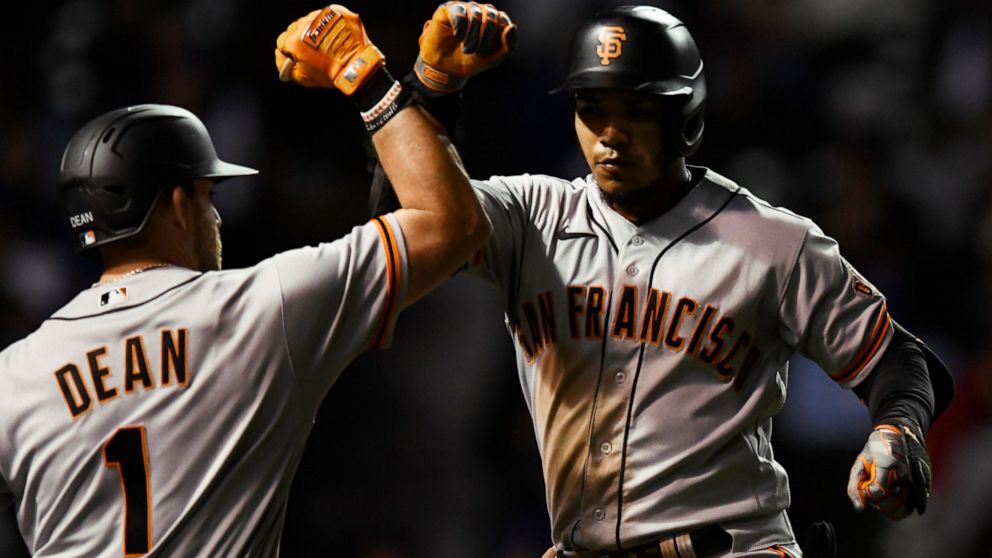 San Francisco Giants' Thairo Estrada, right, celebrates with teammate Austin Dean (1) after hitting a solo home run during the seventh inning of a baseball game against the Chicago Cubs Sunday, Sept. 11, 2022, in Chicago. (AP Photo/Paul Beaty)