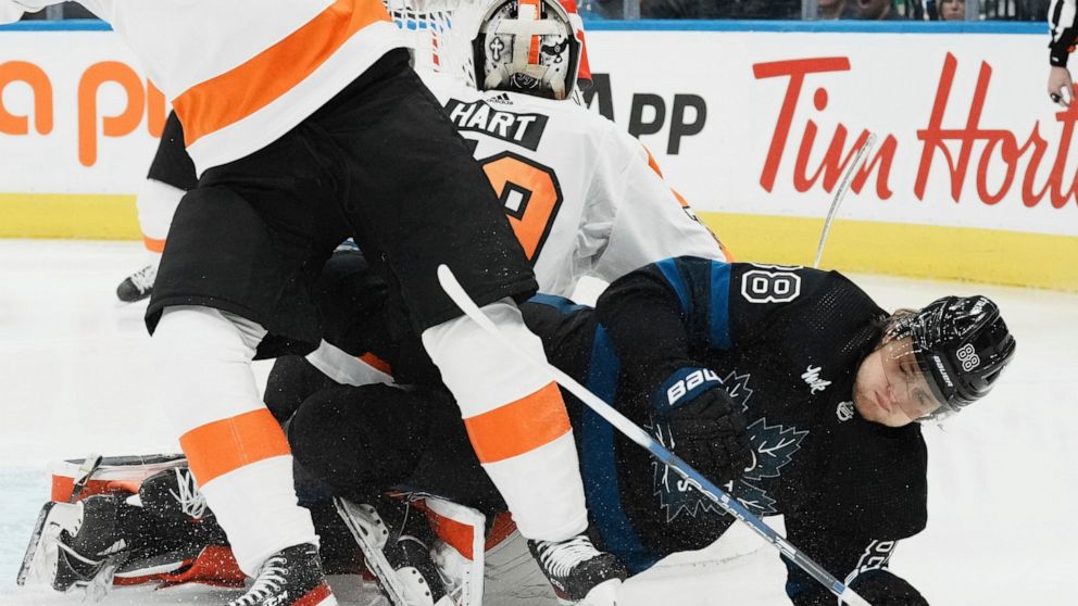 Toronto Maple Leafs right wing William Nylander (88) falls to the ice near Philadelphia Flyers goaltender Carter Hart (79) during the second period of an NHL hockey game, Thursday, Dec. 22, 2022 in Toronto. (Chris Young/The Canadian Press via AP)