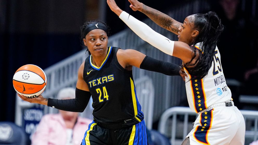 Dallas Wings guard Arike Ogunbowale (24) holds off Indiana Fever guard Tiffany Mitchell (25) in the first half of a WNBA basketball game in Indianapolis, Sunday, July 24, 2022. (AP Photo/Michael Conroy)