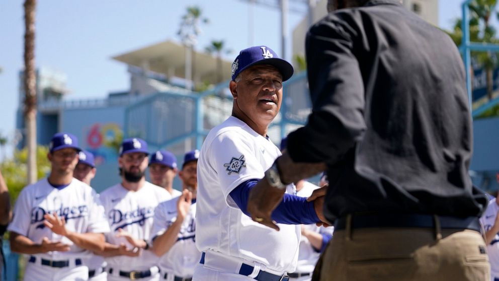 Los Angeles Dodgers' manager Dave Roberts, center, shakes hands with David Robinson, son of Jackie Robinson, before a baseball game between the Cincinnati Reds and the Los Angeles Dodgers in Los Angeles, Friday, April 15, 2022. Today MLB celebrates J