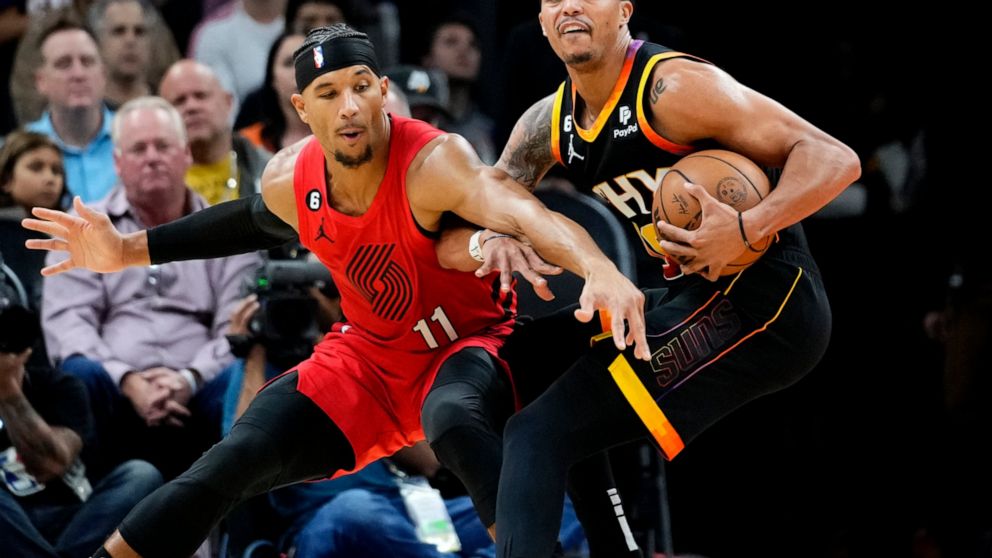 Phoenix Suns guard Damion Lee, spins around Portland Trail Blazers guard Josh Hart (11) during the first half of an NBA basketball game, Friday, Nov. 4, 2022, in Phoenix. (AP Photo/Matt York)