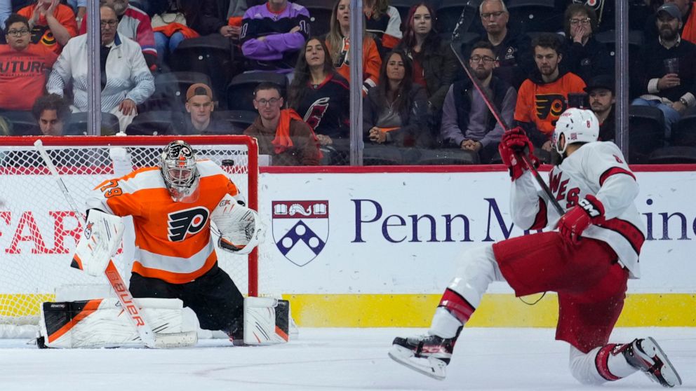 Carolina Hurricanes' Brent Burns, right, scores the game-winning goal against Philadelphia Flyers' Carter Hart during overtime in an NHL hockey game, Saturday, Oct. 29, 2022, in Philadelphia. (AP Photo/Matt Slocum)