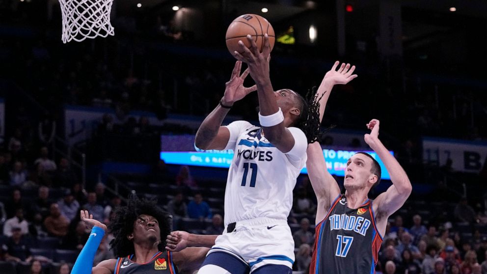 Minnesota Timberwolves center Naz Reid (11) goes to the basket between Oklahoma City Thunder forward Jalen Williams (8) and forward Aleksej Pokusevski (17) in the first half of an NBA basketball game Friday, Dec. 16, 2022, in Oklahoma City. (AP Photo