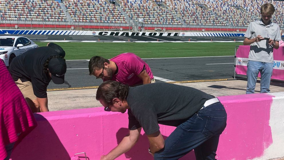 NASCAR driver Kurt Busch, foreground, helps paint the pit wall pink during 10th annual recognition of Breast Cancer Awareness Month at Charlotte Motor Speedway in Concord, N.C., Tuesday, Sept. 27, 2022. (AP Photo/Jenna Fryer)