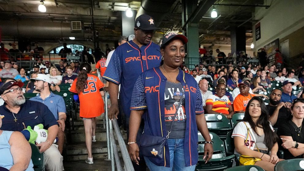 The parents of Houston Astros' Yordan Alvarez, Agustín Eduardo Álvarez Salazar, rear, and Mailyn Cadogan Reyes walk to their seats to watch the Minnesota Twins and Houston Astros play a baseball game Tuesday, Aug. 23, 2022, in Houston. Alvarez's pare