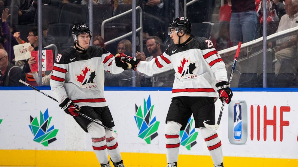 Canada's Zack Ostapchuk (20) and William Dufour (25) celebrate a goal against Latvia during the third period of an IIHF junior world hockey championships game Wednesday, Aug. 10, 2022, in Edmonton, Alberta. (Jason Franson/The Canadian Press)