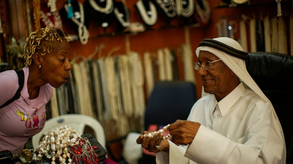 A former pearl diver Saad Ismail talks to a client in his pearl shop in Souq Waqif market in Doha, Qatar, Saturday, Nov. 19, 2022. Pearl fishing drove Qatar’s economy until the 1930s. The dangerous, seasonal trade employed nearly all the former Briti