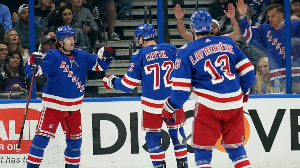 New York Rangers defenseman Jacob Trouba, left, celebrates with teammates, including center Filip Chytil, center, and left wing Alexis Lafrenière, right, after scoring against the Tampa Bay Lightning during the second period of an NHL hockey game Sat