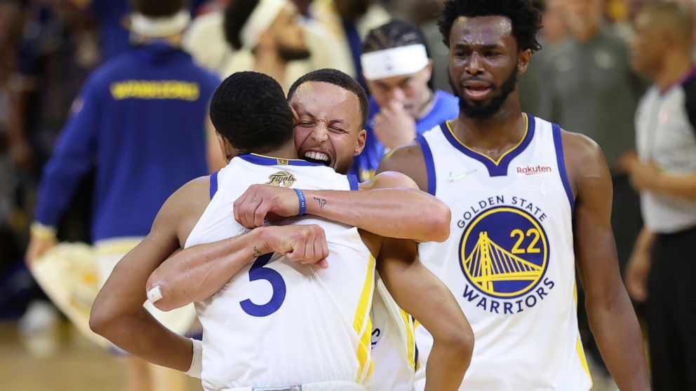Golden State Warriors guard Jordan Poole, left, celebrates with guard Stephen Curry, middle, and forward Andrew Wiggins (22) after scoring against the Boston Celtics during the second half of Game 1 of basketball's NBA Finals in San Francisco, Sunday