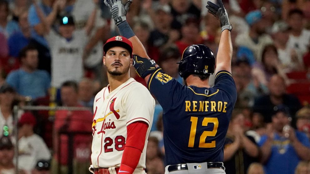 Milwaukee Brewers' Hunter Renfroe (12) celebrates alongside St. Louis Cardinals third baseman Nolan Arenado (28) after hitting an RBI triple during the 10th inning of a baseball game Saturday, Aug. 13, 2022, in St. Louis. (AP Photo/Jeff Roberson)