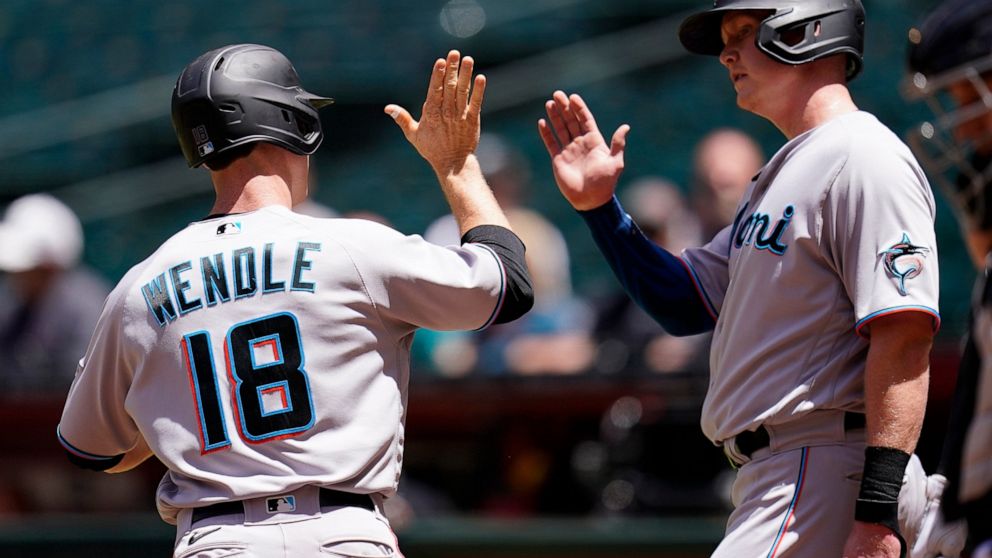 Miami Marlins' Joey Wendle (18) celebrates his two-run home run against the Arizona Diamondbacks with Marlins' Garrett Cooper, right, during the first inning of a baseball game Wednesday, May 11, 2022, in Phoenix. (AP Photo/Ross D. Franklin)