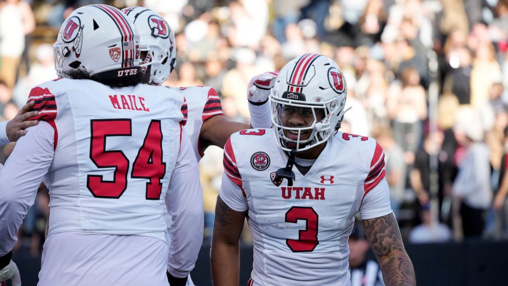 Utah quarterback Ja'Quinden Jackson, right, is congratulated by offensive lineman Paul Maile after running for a touchdown in the first half of an NCAA college football game against Colorado, Saturday, Nov. 26, 2022, in Boulder, Colo. (AP Photo/David