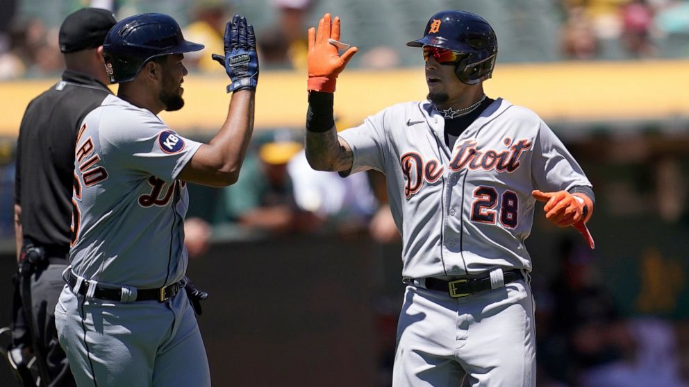 Detroit Tigers' Jeimer Candelario, left, celebrates with Javier Baez after both scored on Robbie Grossman's two-run double during the third inning of the first baseball game of a doubleheader against the Oakland Athletics in Oakland, Calif., Thursday