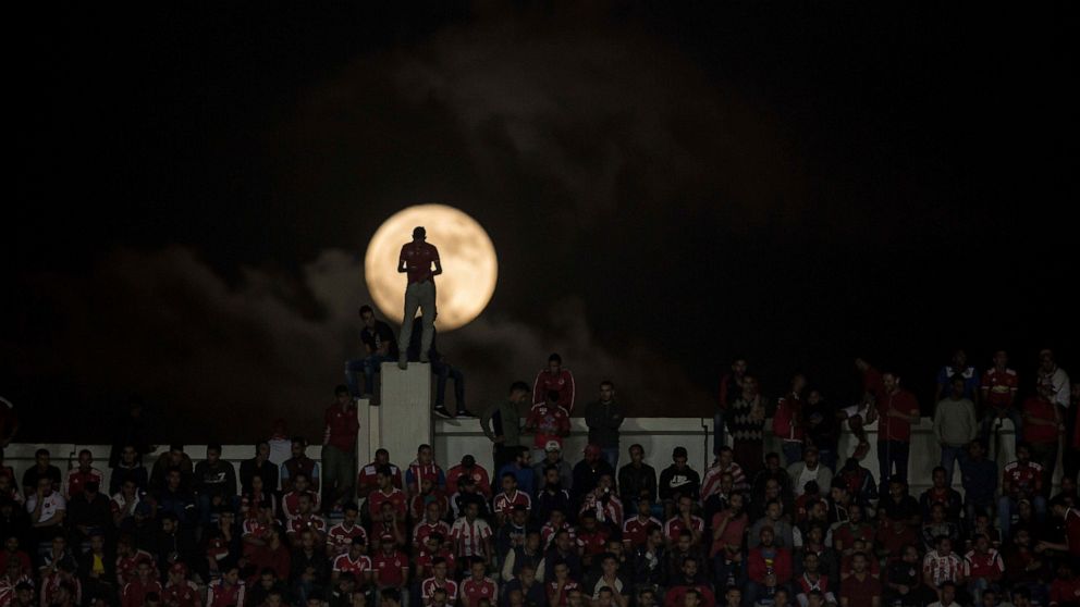 A full moon rises over supporters of Wydad Athletic Club during the second leg of the CAF Champions League final against Egypt's Al Ahly Sporting Club, in Casablanca, Morocco, Saturday, Nov. 5, 2017. Wydad defeated Al Ahly 2-1 on aggregate to win the