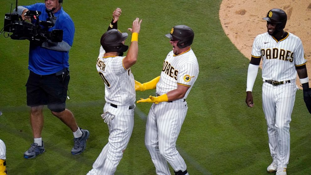 San Diego Padres' Luke Voit, center, celebrates with Eric Hosmer, left, after hitting a three-run home run against the Pittsburgh Pirates during the sixth inning of a baseball game Friday, May 27, 2022, in San Diego. (AP Photo/Gregory Bull)