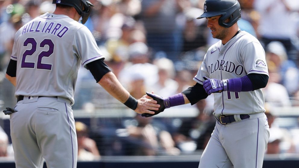 Colorado Rockies' Sam Hilliard, left, celebrates with Jose Iglesias, right, after crossing home plate on a two-RBI double by Ryan McMahon against the San Diego Padres during the eighth inning of a baseball game Sunday, June 12, 2022, in San Diego. (A