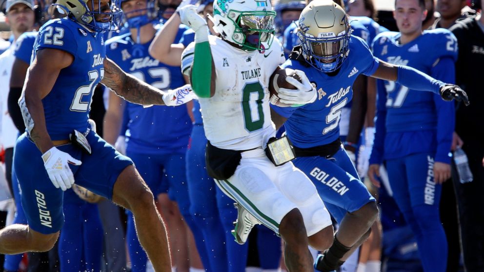 Tulane's Shaadie Clayton-Johnson completes a long gain while being forced out of bounds by Tulsa defenders LJ Wallace, left, and Kenney Solomon during an NCAA college football game in Tulsa, Okla. on Saturday, Nov. 5, 2022. (AP Photo/Dave Crenshaw)