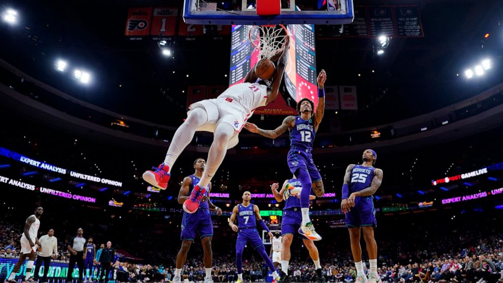 Philadelphia 76ers' Joel Embiid, left, dunks past Charlotte Hornets' Kelly Oubre Jr. during the first half of an NBA basketball game, Sunday, Dec. 11, 2022, in Philadelphia. (AP Photo/Matt Slocum)