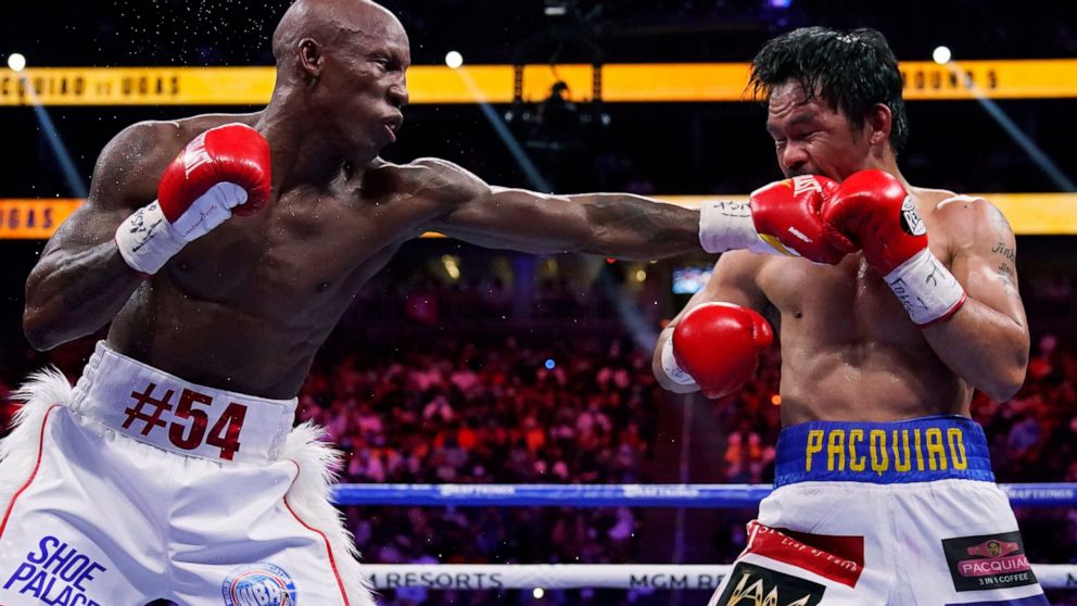 FILE - Yordenis Ugás, of Cuba, hits Manny Pacquiao, of the Philippines, in a welterweight championship boxing bout Aug. 21, 2021, in Las Vegas. Ugás faces Errol Spence Jr. in a unification bout Saturday, April 16. (AP Photo/John Locher, File)