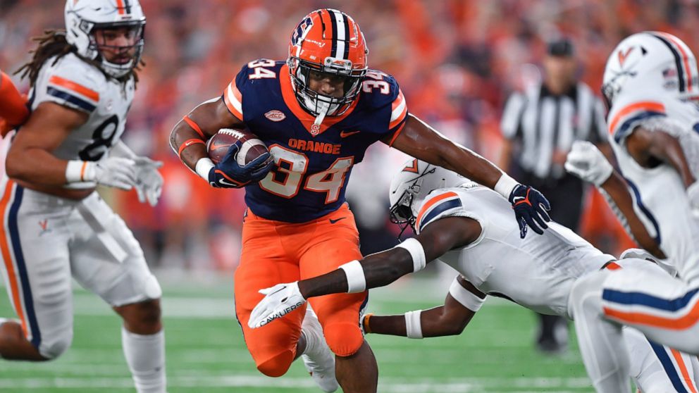 Syracuse running back Sean Tucker (34) tries to break a tackle by Virginia cornerback Anthony Johnson during the first half of an NCAA college football game Friday, Sept. 23, 2022, in Syracuse, N.Y. (AP Photo/Adrian Kraus)