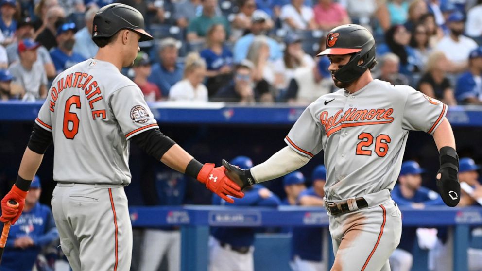 Baltimore Orioles' Ryan McKenna, right, celebrates with Ryan Mountcastle after scoring against the Toronto Blue Jays during the first inning of a baseball game Monday, Aug. 15, 2022, in Toronto. (Jon Blacker/The Canadian Press via AP)