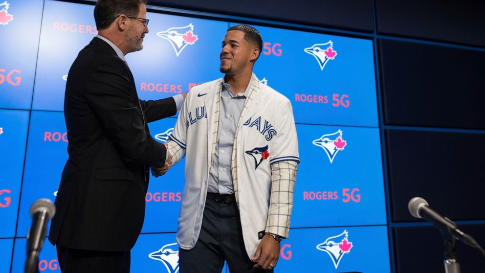 Ross Atkins, executive vice president of baseball operations and general manager of the Toronto Blue Jays, left, shakes hands with pitcher José Berríos during a press conference announcing his seven-year extension with the team at Rogers Centre in To