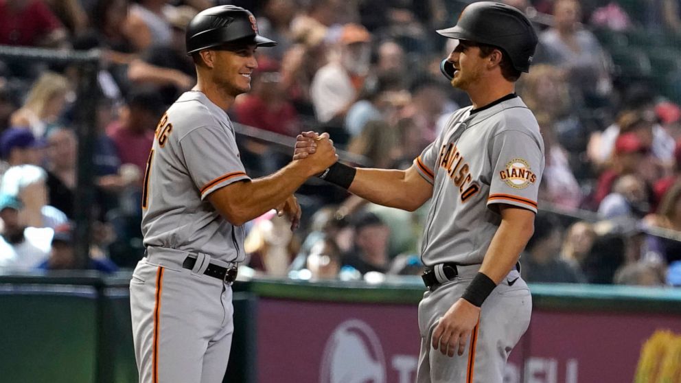 San Francisco Giants third base coach Mark Hallberg, left, congratulates Ford Proctor, right, for getting his first hit in the major leagues in the seventh inning of a baseball game against the Arizona Diamondbacks Sunday Sept. 25, 2022, in Phoenix. 