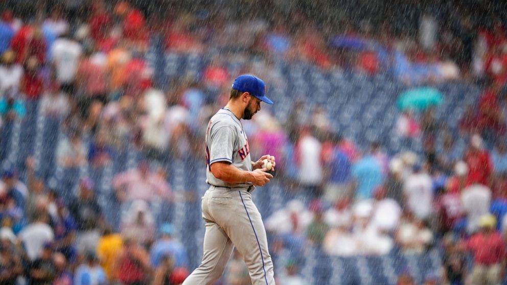 New York Mets pitcher Nate Fisher walks to the mound in a rain storm during the sixth inning of a baseball game against the Philadelphia Phillies, Sunday, Aug. 21, 2022, in Philadelphia. (AP Photo/Matt Slocum)