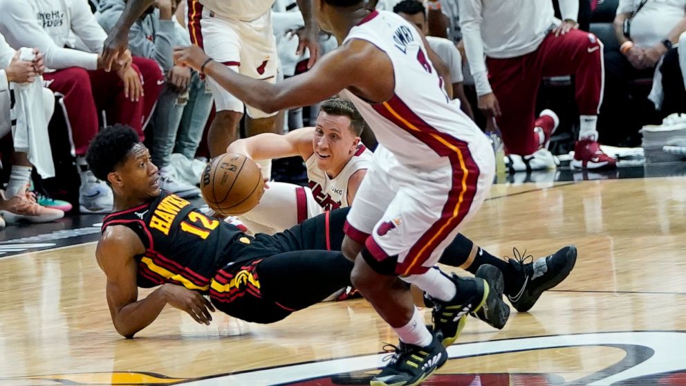Atlanta Hawks forward De'Andre Hunter (12) and Miami Heat guard Duncan Robinson go for a loose ball during the first half of Game 1 of an NBA basketball first-round playoff series, Sunday, April 17, 2022, in Miami. (AP Photo/Lynne Sladky)