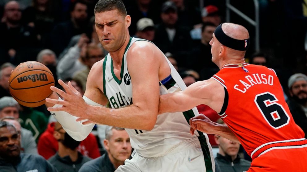 Milwaukee Bucks' Brook Lopez tries to get past Chicago Bulls' Alex Caruso during the first half of an NBA basketball game Tuesday, March 22, 2022, in Milwaukee . (AP Photo/Morry Gash)