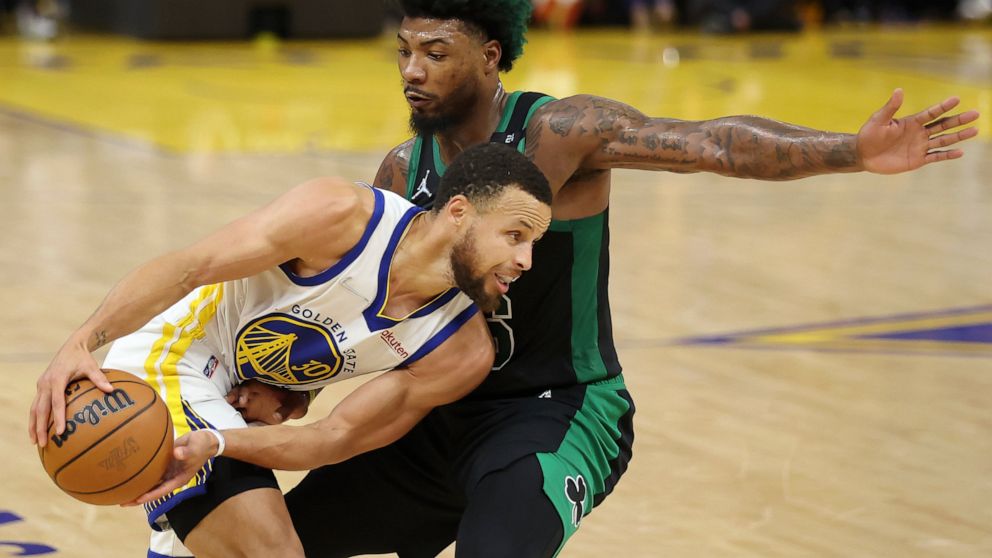 Golden State Warriors guard Stephen Curry, left, is defended by Boston Celtics guard Marcus Smart during the first half of Game 5 of basketball's NBA Finals in San Francisco, Monday, June 13, 2022. (AP Photo/Jed Jacobsohn)