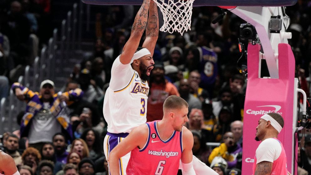 Los Angeles Lakers forward Anthony Davis, left, dunks against Washington Wizards centers Daniel Gafford (21) and Kristaps Porzingis (6) during the second half of an NBA basketball game, Sunday, Dec. 4, 2022, in Washington. The Lakers won 130-119. (AP