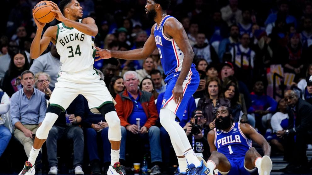 Milwaukee Bucks' Giannis Antetokounmpo, left, tries to get around Philadelphia 76ers' Joel Embiid, center, and James Harden during the first half of an NBA basketball game, Thursday, Oct. 20, 2022, in Philadelphia. (AP Photo/Matt Slocum)
