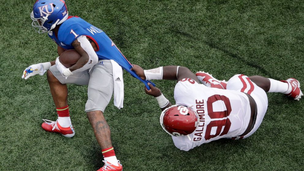 Oklahoma defensive lineman Neville Gallimore (90) tackles Kansas running back Pooka Williams Jr. (1) during the first half of an NCAA college football game Saturday, Oct. 5, 2019, in Lawrence, Kan. (AP Photo/Charlie Riedel)