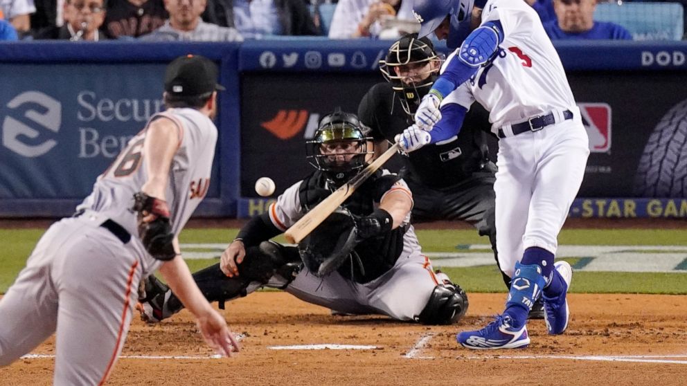 Los Angeles Dodgers' Chris Taylor, right, hits a two RBI single as San Francisco Giants starting pitcher Carlos Rodon, left, and catcher Joey Bart, second from left, watch along with home plate umpire Dan Merzel during the second inning of a baseball