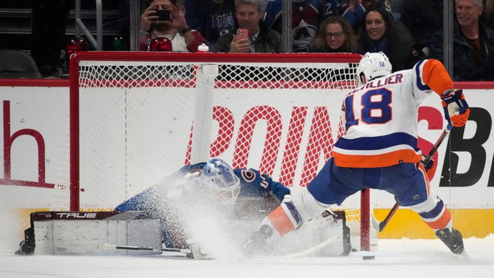 Colorado Avalanche goaltender Alexandar Georgiev, left, stops a shot off the stick of New York Islanders left wing Anthony Beauvillier during a shootout in of an NHL hockey game, Monday, Dec. 19, 2022, in Denver. (AP Photo/David Zalubowski)