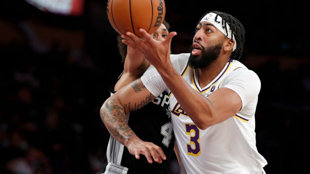 Los Angeles Lakers forward Anthony Davis, right, goes up against San Antonio Spurs guard Derrick White during the first half of an NBA basketball game Sunday, Nov. 14, 2021, in Los Angeles. (AP Photo/Alex Gallardo)