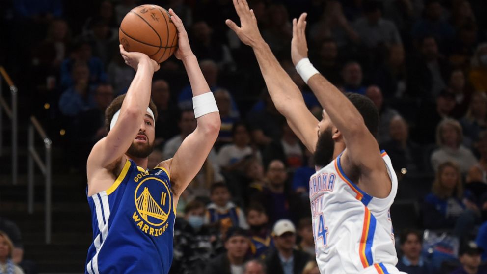 Golden State Warriors guard Klay Thompson, left, shoots the ball over Oklahoma City Thunder guard Kenrich Williams in the first half of an NBA basketball game, Monday, Feb. 7, 2022, in Oklahoma City. (AP Photo/Kyle Phillips)
