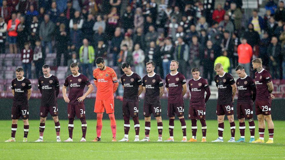 Hearts players stand wearing black armbands before the second half following the announcement of the death of Queen Elizabeth II, during the Europa Conference League Group A soccer match between Heart of Midlothian and Istanbul Basaksehir at Tynecast