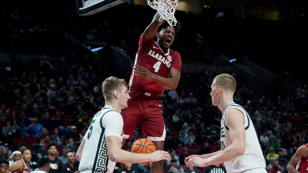 Alabama forward Noah Gurley (4) dunks over Michigan State guard Tre Holloman, left, and forward Joey Hauser during the first half of an NCAA college basketball game in the Phil Knight Invitational tournament in Portland, Ore., Thursday, Nov. 24, 2022