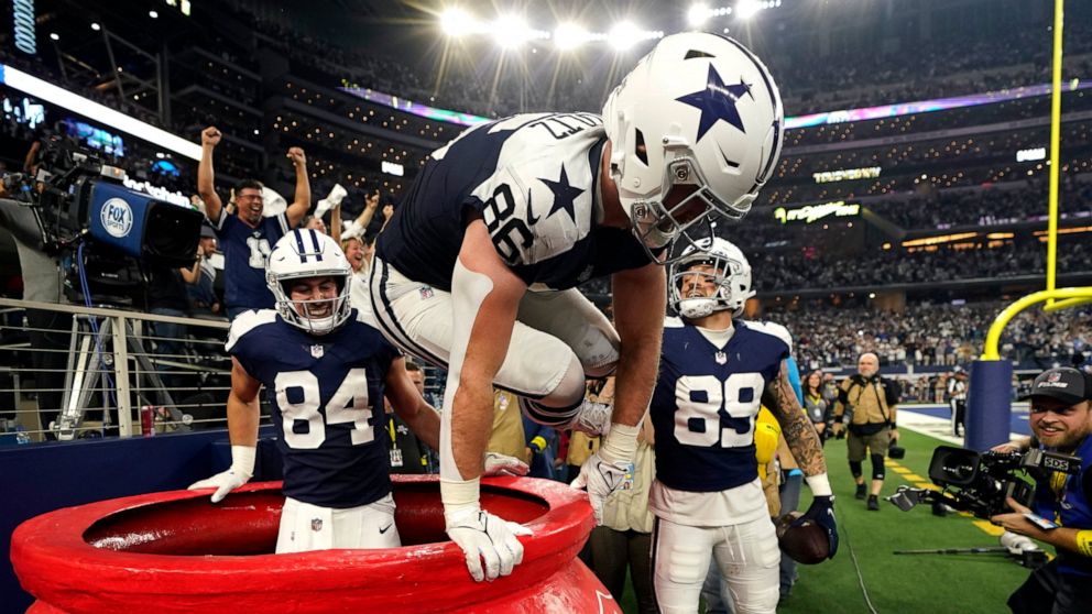Dallas Cowboys' Dalton Schultz (86) jumps out of a Salvation Army kettle while celebrating Peyton Hendershot's (89) touchdown along with Sean McKeon (84) during the second half of an NFL football game against the New York Giants Thursday, Nov. 24, 20