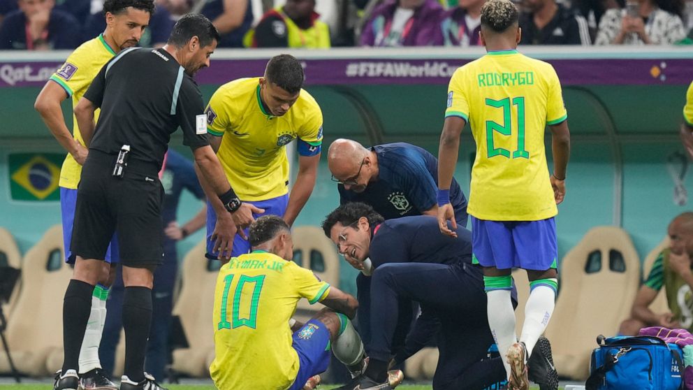 Brazil's Neymar, bottom, is treated by members of his team during the World Cup group G soccer match between Brazil and Serbia, at the Lusail Stadium in Lusail, Qatar, Thursday, Nov. 24, 2022. (AP Photo/Aijaz Rahi)